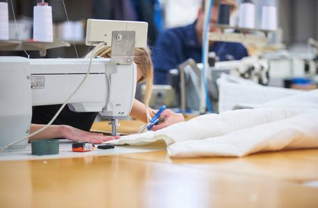 在一家纺织厂女裁缝线程蓝色纺织集中裁缝把纺织品放在桌子上, 用胶带